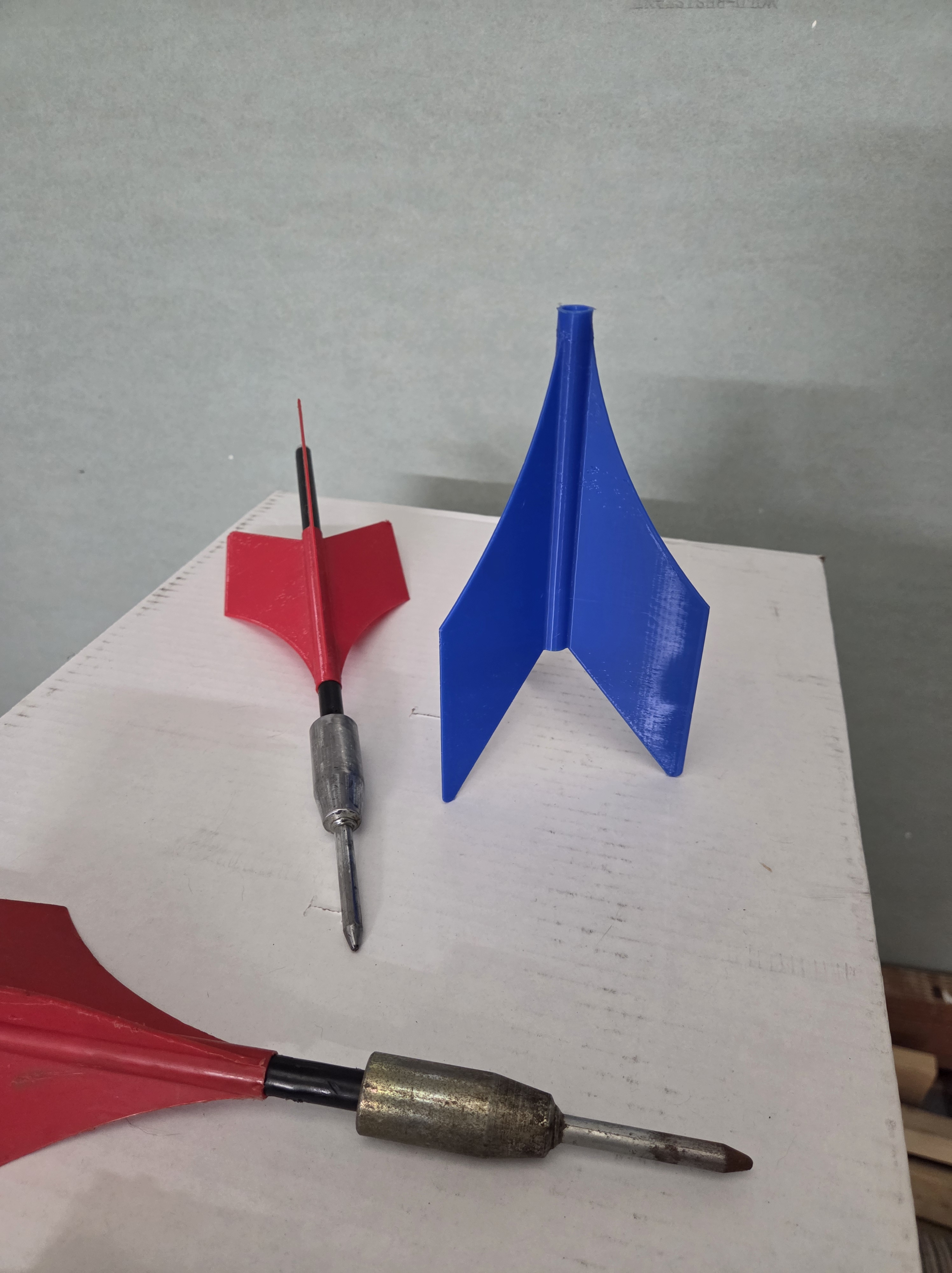 Side-by-side comparison of a rusted vintage lawn jart and a new red 3D-printed fin assembly