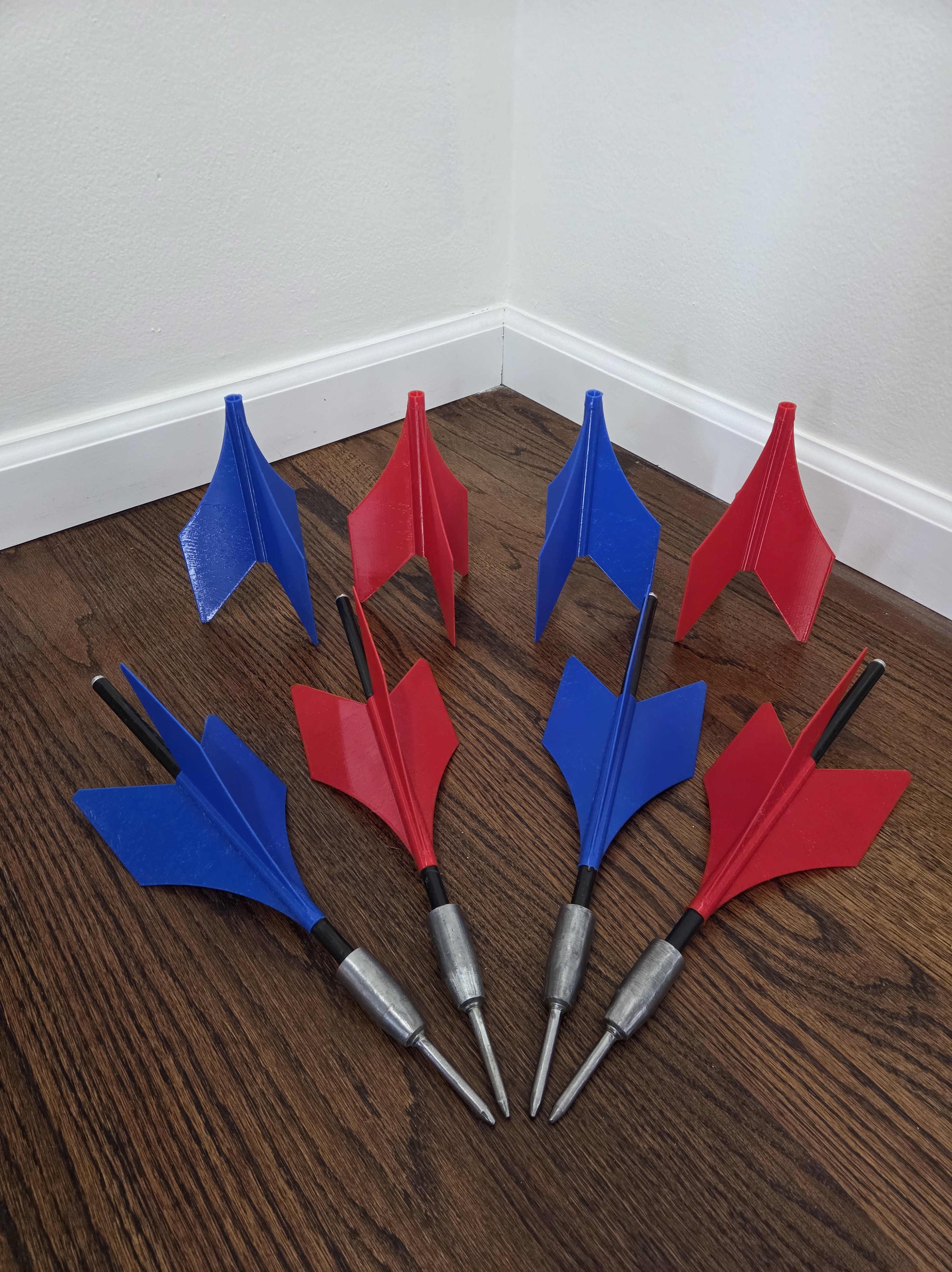 Completed set of four restored lawn jarts with red and blue fins fanned out on a hardwood floor